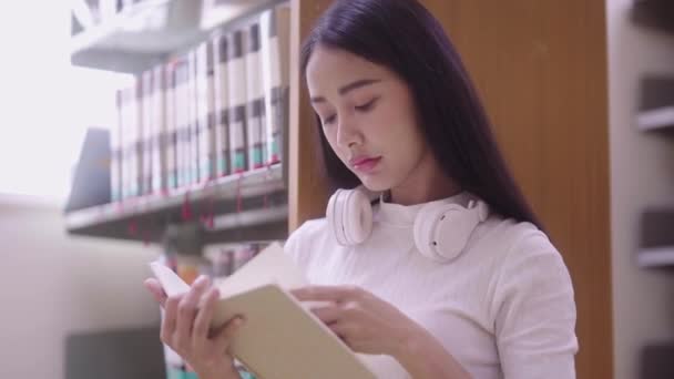 Ασιατική Γυναίκα Φοιτητής Ανάγνωση Βιβλίο Κάθεται Στο Πάτωμα Από Βιβλιοθήκη — Αρχείο Βίντεο