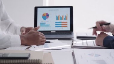 Asyalı iş adamı takım arkadaşı ile konuşuyor, dizüstü bilgisayarla bir projeyi sunuyor ve tartışıyor. Modern ofis ortamında kasıtlı bir işe giriştim.