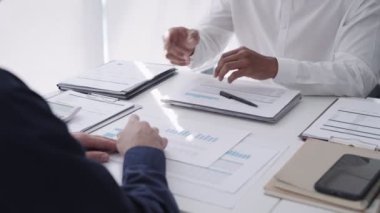 Asyalı iş adamı takım arkadaşı ile işbirliği yapıyor, modern ofis ortamında bir proje üzerinde özenle el ele tutuşuyor.. 