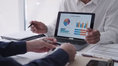 Asyalı iş adamı takım arkadaşı ile konuşuyor, dizüstü bilgisayarla bir projeyi sunuyor ve tartışıyor. Modern ofis ortamında kasıtlı bir işe giriştim.