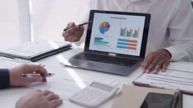 Asyalı iş adamı takım arkadaşı ile konuşuyor, dizüstü bilgisayarla bir projeyi sunuyor ve tartışıyor. Modern ofis ortamında kasıtlı bir işe giriştim.
