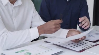 İş adamı, modern ofis ortamında özenle çalışan bir iş arkadaşıyla proje tartışıyor. Takım çalışması ve proje işbirliği gösteriliyor 