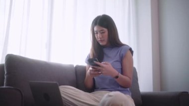Sosyal medyada sörf yapan güzel bir Asyalı kadın ya da evdeki oturma odasında dinlenirken dizüstü bilgisayarda çalışan bir kadın oturma odasında faaliyet kavramı. Yüksek kalite 4k görüntü