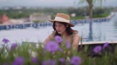 Asyalı Serbest Kadın, yaz tatili boyunca internette ya da bilgisayarla yüzme havuzunun yakınında herhangi bir yerde çalışarak öğrenim görüyor. Yüksek kalite 4k görüntü