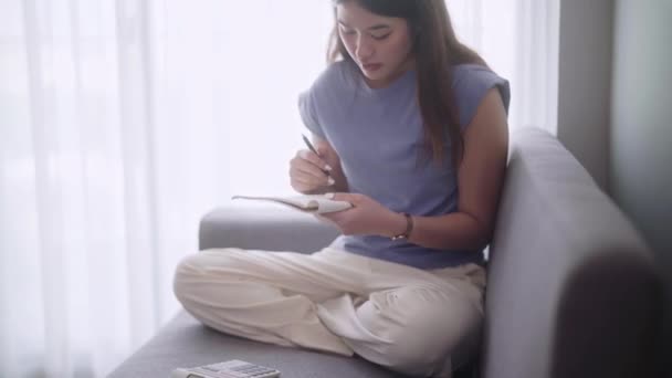 Młoda Azjatka Siedzi Sofie Używając Kalkulatora Obliczania Dochodów Wydatków Lub — Wideo stockowe