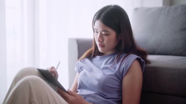 Junge Asiatin Schreibt Mit Stift Neue Projektideen Auf Tablet Während — Stockvideo