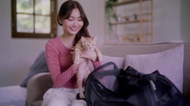 Asyalı bir kadın kediyi özel bir plastik kafes taşıyıcısının içinde tutuyor. Evcil hayvan konsepti olan kanepede mutlu bir duygu taşıyor. Yüksek kalite 4k görüntü