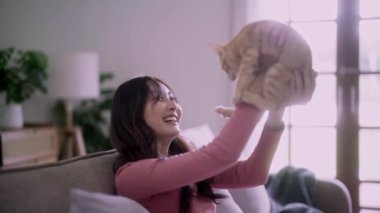 Genç Asyalı bir kadın, sevimli kediciği kucağında tutuyor. Kollarında mutlu duygular, sevimli evcil hayvan konsepti. Yüksek kalite 4k görüntü