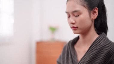 Asian woman applying face powder in front of a large mirror after washing and styling her hair at home. Showcase her beauty routine for enhanced sales and skincare awareness. High quality 4k footage