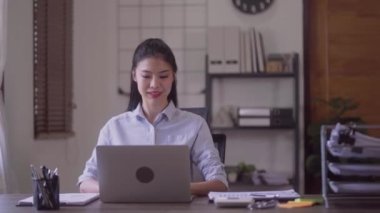 Young Successful Asian Businesswoman Sitting at Desk Working on Laptop Computer Woman working with Big Data e-Commerce in office. High quality 4k footage