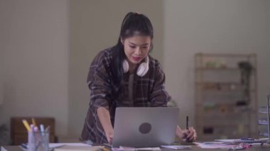 Young Asian Women Graphic designer Artist work on computer laptop and with graphic interactive drawing pen sitting in front of window at desk in office. High quality 4k footage