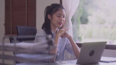 Young Asian business woman talking leading hybrid conference discussing project remote video call virtual meeting by using computer from home office. High quality 4k footage