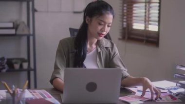 Young Asian Women Graphic designer Artist work on computer laptop and with graphic interactive drawing pen sitting in front of window at desk in office. High quality 4k footage