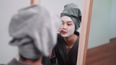 An Asian woman is applying a face mask for a rejuvenating skincare routine, nurturing her skins health and radiance at her home. Capture the essence of self-care and wellness