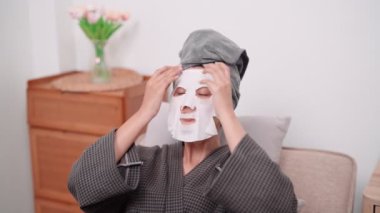 An Asian woman is applying a face mask for a rejuvenating skincare routine, nurturing her skins health and radiance at her home. Capture the essence of self-care and wellness
