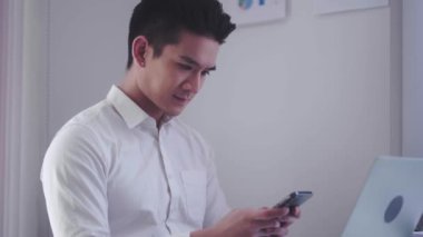 Asian businessman holding smartphone for chat online mobile applications sitting in office, Inspiring productivity with a wealth of technology. High quality 4k footage