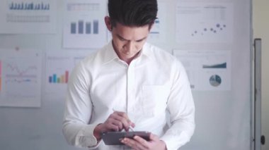 Businessman working on tablet while holding pen and reading document and making edits on table at office, paperless office, digital document concept. High quality 4k footage