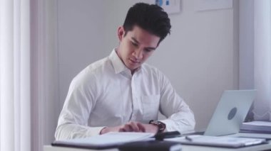 Serious Asian businessman in office using calculator and laptop for work and calculate financial expenses at workplace. High quality 4k footage
