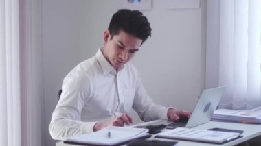 Serious Asian businessman in office using calculator and laptop for work and calculate financial expenses at workplace. High quality 4k footage