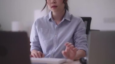 Young Asian woman hard working with documents at her using laptop computer with analytical charts and graphs at her home, work from home concept. High quality 4k footage