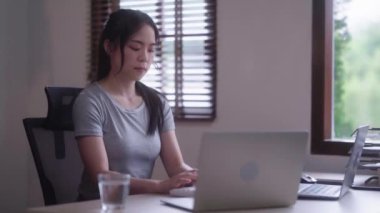 Young Asian woman hard working with documents at her using laptop computer with analytical charts and graphs at her home, work from home concept. High quality 4k footage