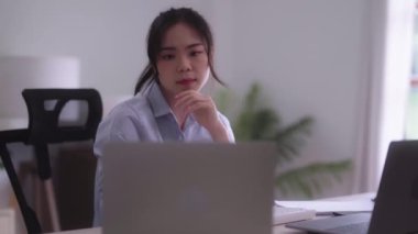 Young Asian woman hard working with documents at her using laptop computer with analytical charts and graphs at her home, work from home concept. High quality 4k footage