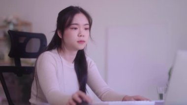 Dizüstü bilgisayarda çalışan uykulu yorgun genç Asyalı kadının gözleri kapanıyor ve evde ilgisiz bir şekilde uykuya dalmak üzere. Yüksek kalite 4k görüntü