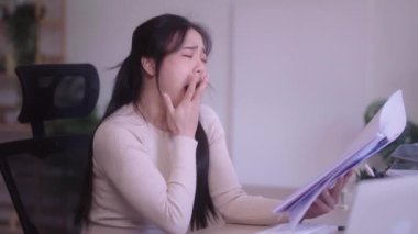 Young Asian woman hard working with documents at her using laptop computer with analytical charts and graphs at her home, work from home concept. High quality 4k footage