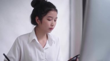 Genç Asyalı kadın serbest grafik tasarımcısı ya da sanatçı rötuşçusu dijital tablet üzerinde stil kalemle çiziyor..