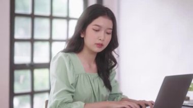 Genç Asyalı üniversite öğrencisi kadınlar evdeki oturma odasında dijital tabletle ve kulaklıkla e-öğrenim görüyorlar, uzaktan eğitim kavramı. Yüksek kalite 4k görüntü