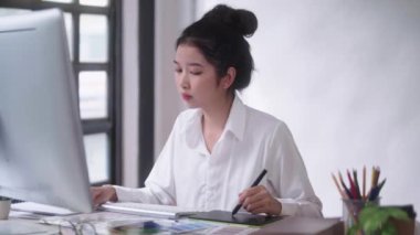 Genç Asyalı kadın serbest grafik tasarımcısı ya da sanatçı rötuşçusu dijital tablet üzerinde stil kalemle çiziyor..