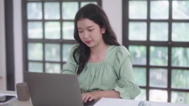 Genç Asyalı üniversite öğrencisi kadınlar evdeki oturma odasında dijital tabletle ve kulaklıkla e-öğrenim görüyorlar, uzaktan eğitim kavramı. Yüksek kalite 4k görüntü