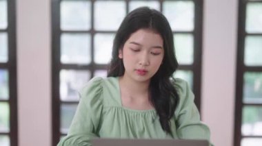 Genç Asyalı üniversite öğrencisi kadınlar evdeki oturma odasında dijital tabletle ve kulaklıkla e-öğrenim görüyorlar, uzaktan eğitim kavramı. Yüksek kalite 4k görüntü