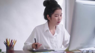Genç Asyalı Grafik Tasarımcı Kadınlar ya da yaratıcı tutuş stili kalem faresi ve seçilen kumaş rengi renk kumaş örnekleri stüdyo ofisindeki masa başı sanat aletleri Palette. Yüksek kalite 4k görüntü