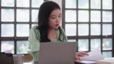 Genç Asyalı üniversite öğrencisi kadınlar evdeki oturma odasında dijital tabletle ve kulaklıkla e-öğrenim görüyorlar, uzaktan eğitim kavramı. Yüksek kalite 4k görüntü