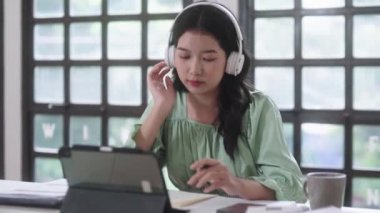 Mutlu Asyalı öğrenci kadınlar kulaklık takıyor ve kütüphane kampüsünde müzik dinlemek için dijital tablet kullanıyorlar. Yüksek kalite 4k görüntü