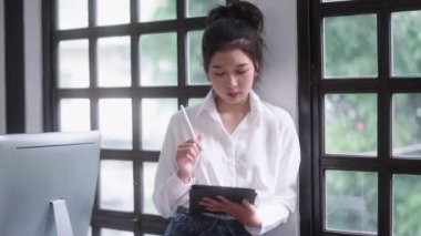Dijital tablet üzerinde dijitalleştirilmiş stilus kalemle çalışan genç Asyalı grafik tasarımcı veya iç mimar kadınlar 