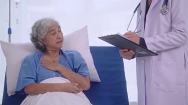 Kıdemli Asyalı doktor klinikteki sağlık kontrolü sırasında yaşlı kadın hastalarla muayene odasında, sağlık hizmetlerinde ya da hastanede konuşuyordu. Yüksek kalite 4k görüntü