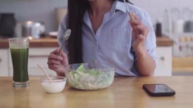 Genç sağlıklı Asyalı kadın marul salatası yiyor ve evde temiz sebzeler yemekten hoşlanıyor. Kilo kaybı ve yaşam tarzı konsepti. Yüksek kalite 4k görüntü