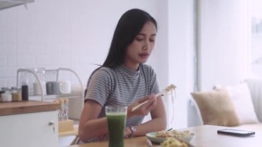 Asyalı genç bir kız yemek yiyor, yemek çubukları yiyor ve Tayland yemeği eriştelerini evde tutuyor. Yüksek kalite 4k görüntü