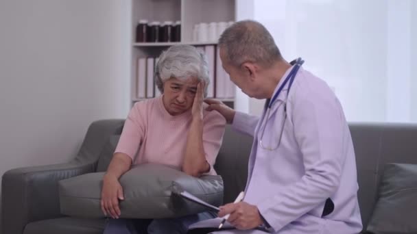 Старший Азиат Врач Назначения Жаловаться Мигрени Терапевт Написания Симптомов Буфер — стоковое видео