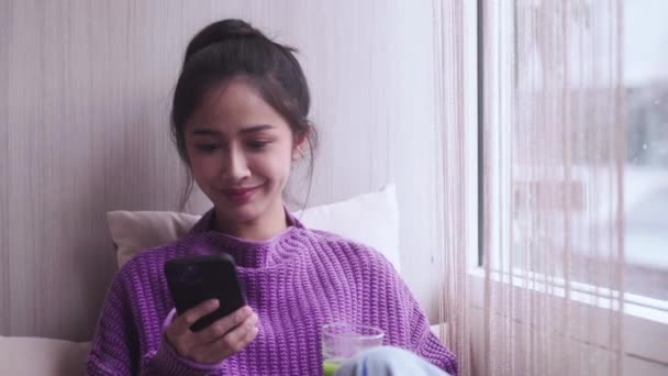 Młode Szczęśliwe Tysiąclecia Zdrowe Azjatki Sprawdzanie Smartfona Podczas Picia Domowej — Wideo stockowe