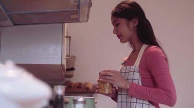 Çekici, mutlu Asyalı kadın ev hanımı evde mutfakta elektrikli ocakta makarna pişiriyor. Yüksek kalite 4k görüntü