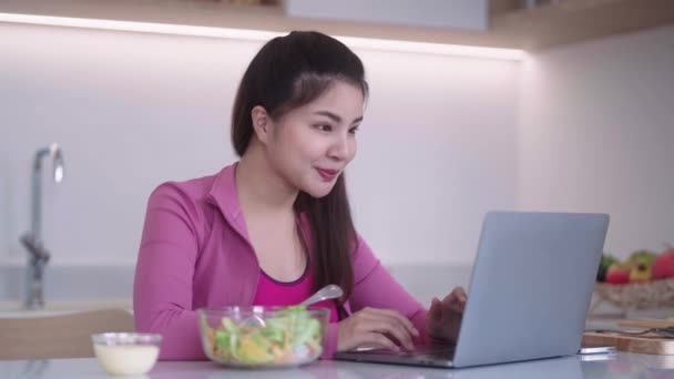 Sporty Ung Asiatisk Kvinde Sportstøj Kigger Bærbar Computer Spiser Grøntsager – Stock-video