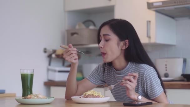 饱餐一顿 亚洲女人端着叉子和勺子在盘子里和桌上吃着亚洲饭 在家里厨房里享受着真正地道的泰国菜 健康的泰国菜 高质量的4K镜头 — 图库视频影像