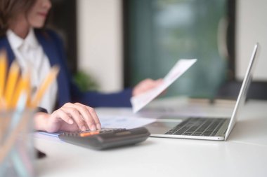 Pazarlama ticaret belgesini okuyan ve hesap makinesi kullanan Asyalı iş kadınları, ofis dışındaki yeni girişimin yatırım ve pazar stoklarını analiz ederken, finans tablosunu kontrol etmek için istatistikleri hesaplarlar..