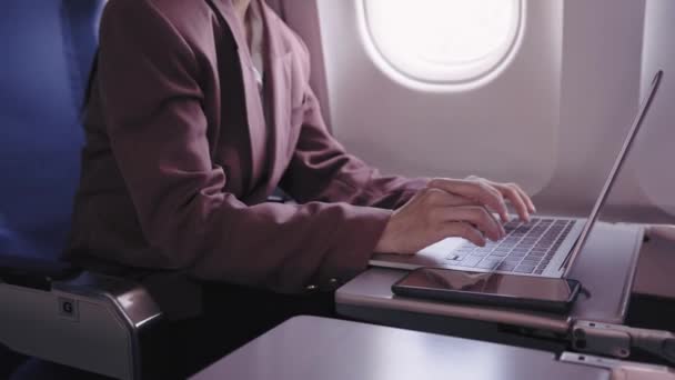 一位亚洲女商人正在她的笔记本电脑上工作 她在飞行过程中积极地记录和分析各项任务 她致力于在运输途中最大限度地提高生产力 — 图库视频影像