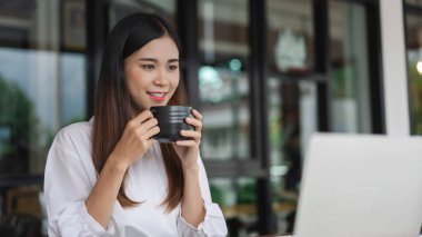 İş kadınları, ofis dışındaki yeni girişimleri analiz etmek için kahve içer ve dizüstü bilgisayarda veri okurlar.