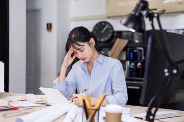 Asyalı mimar kadınlar mimari projenin tasarımı ve not defterine notlar yazmayı düşünürken aynı zamanda bina ve inşaat mimarisi planı üzerinde çalışıyorlar..