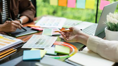 İki yaratıcı grafik tasarımcısı proje tasarlamak ve tablet üzerinde çizim yapmak için renk örnekleri hakkında tartışır.